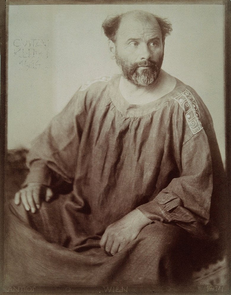 Gustav Klimt en blouse de peintre, photographie de 1914 — Wikimedia Commons.